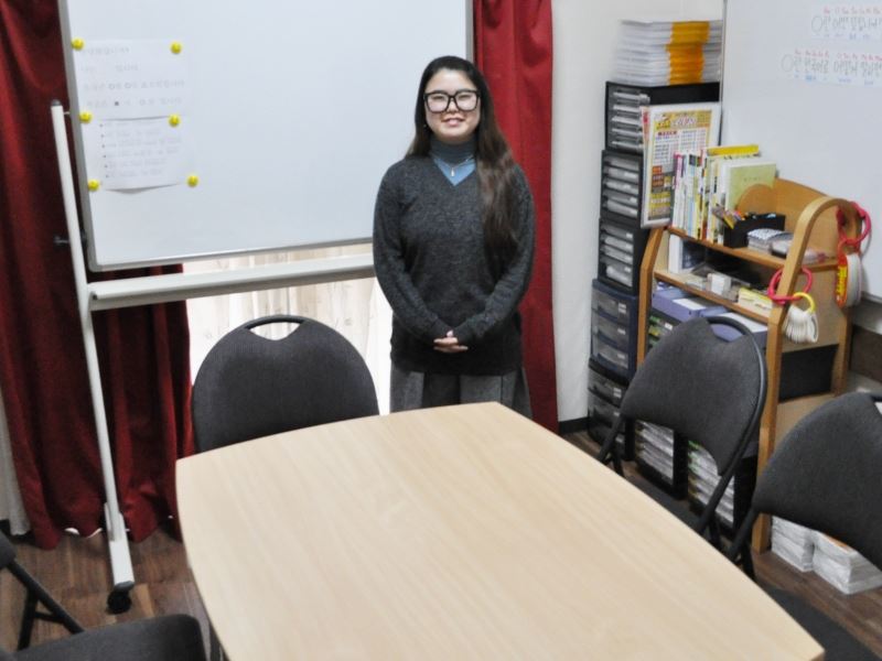 Koga Sensei sitting in front of the whiteboard, at the Fuji Japanese Language School Fukuoka in 2018.